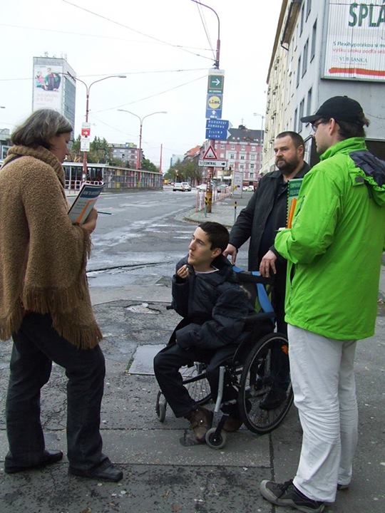 boy in a wheelchair, three other people standing on a sidewalk